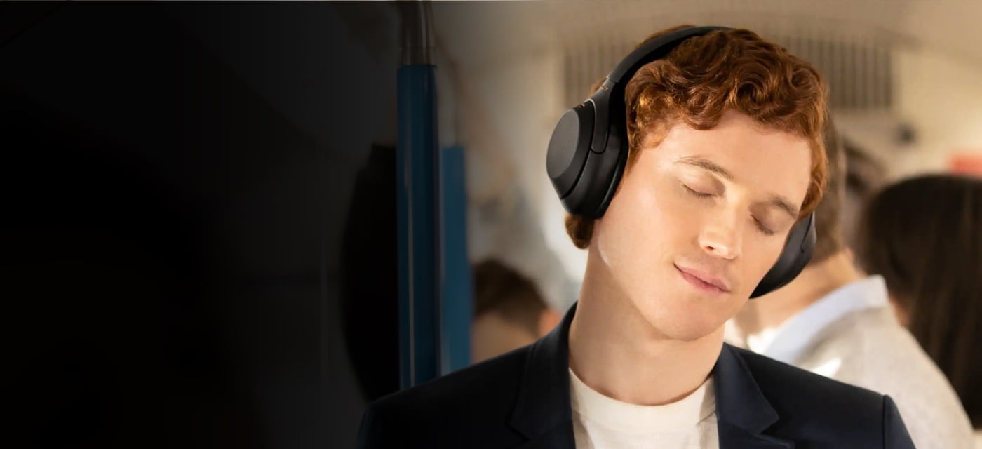 man with eyes closed using Black Sony WH1000M4 noise cancelling headphones on a bus