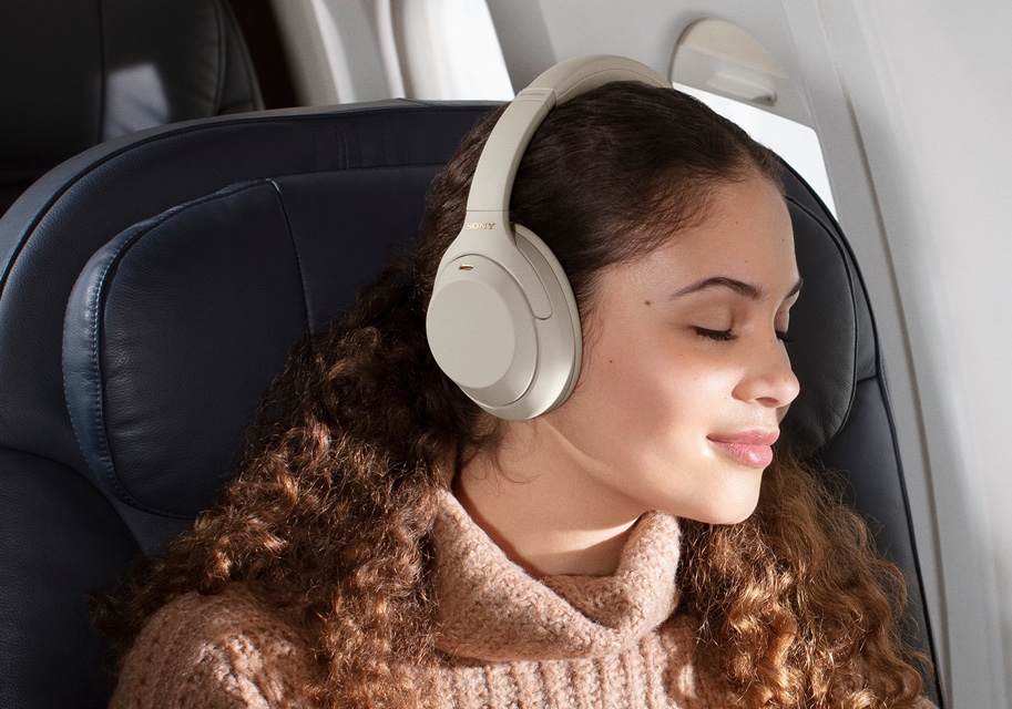 woman with eyes closed on plane using WH1000M4/S noise cancelling headphones