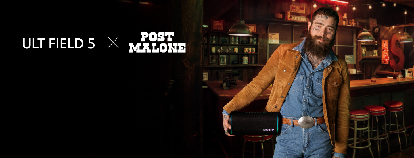 Post Malone in denim and a brown jacket holds a Sony speaker in a cozy bar setting. "ULT FIELD 5 x POST MALONE" text is visible on the left. Warm, inviting atmosphere.