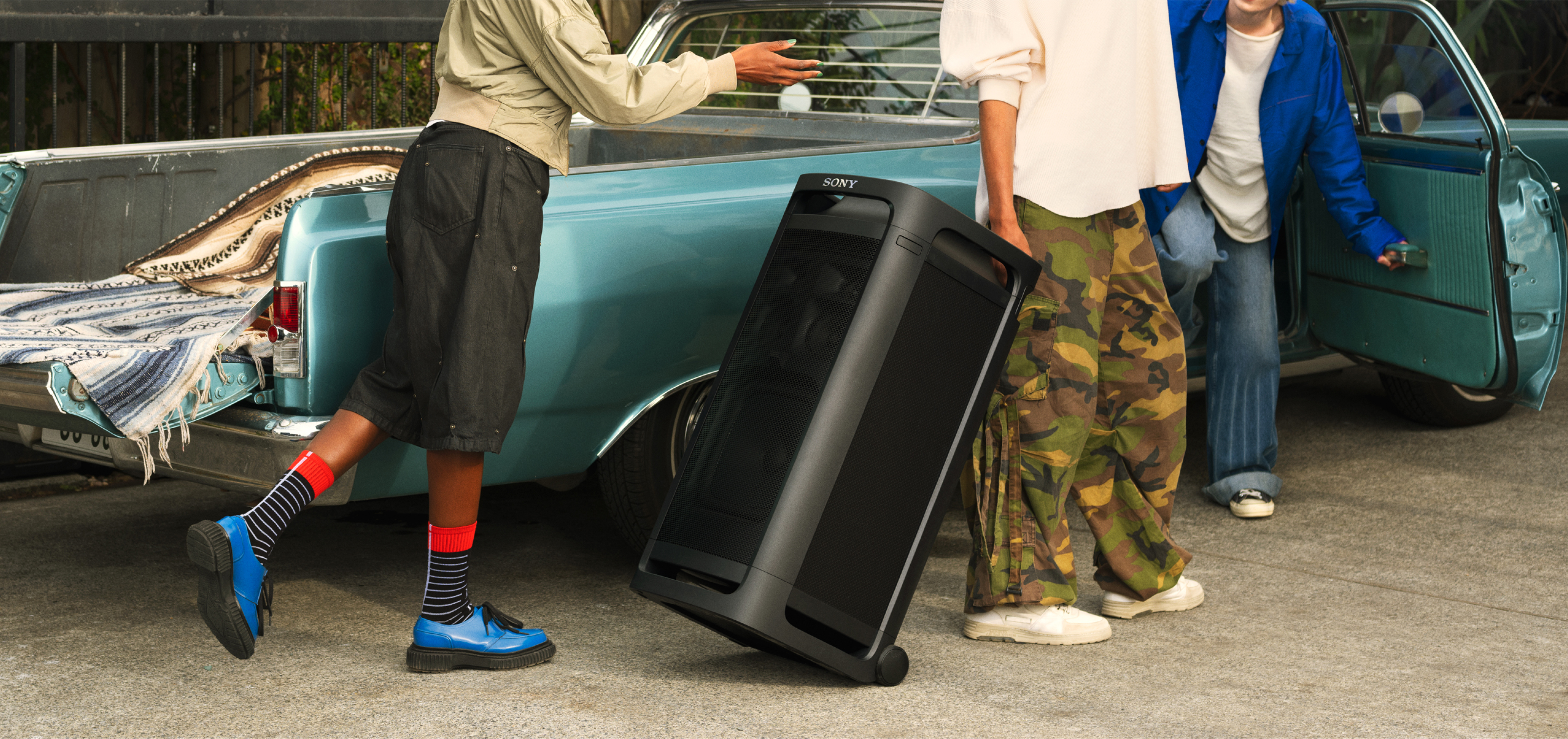 A person pulling the TOWER 9AC speaker behind them using the 2 castors on the base of the speaker