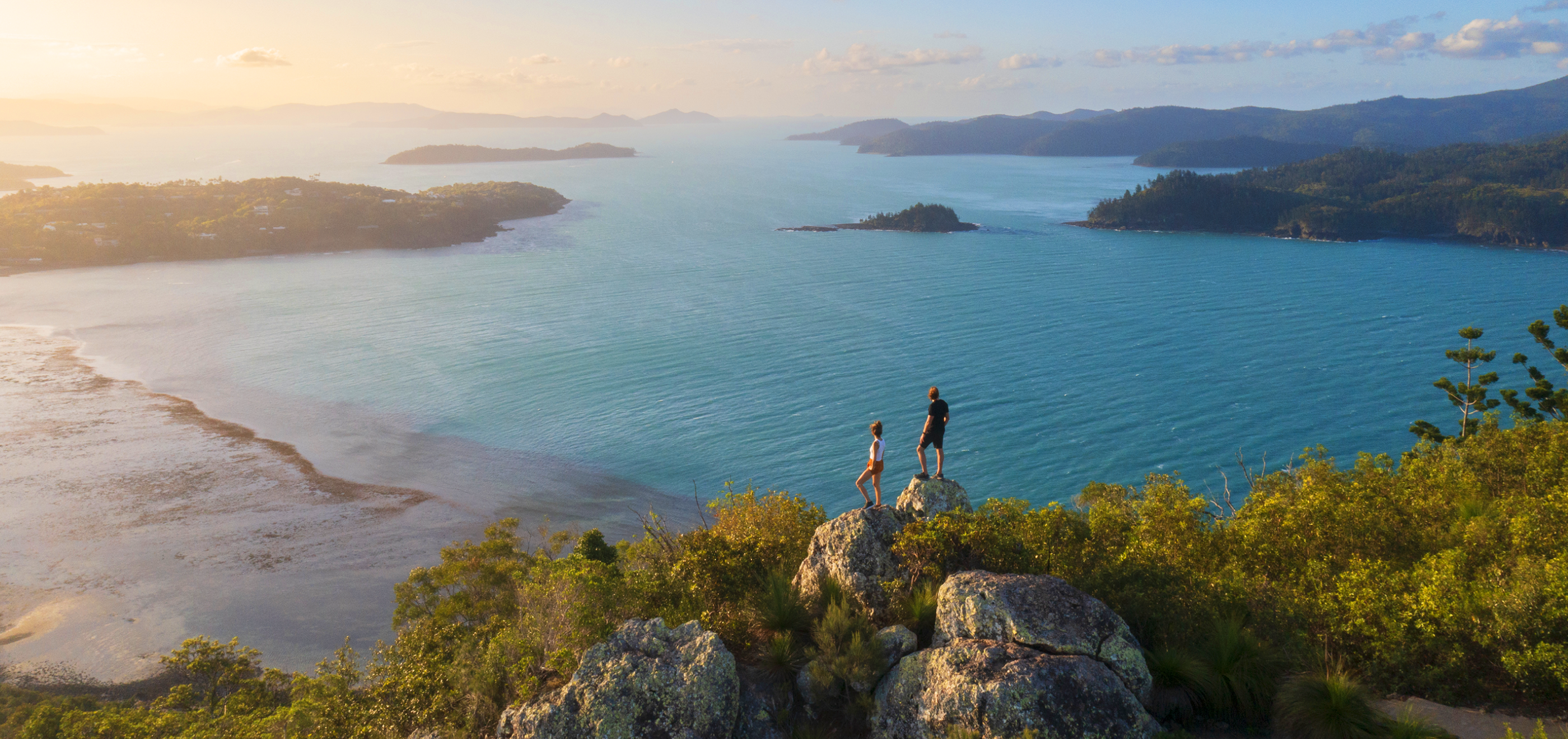 Image of two people on a rock looking at the sea.