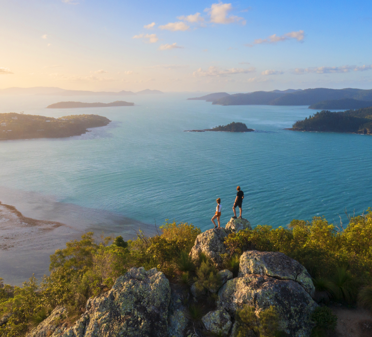 Image of two people on a rock looking at the sea.